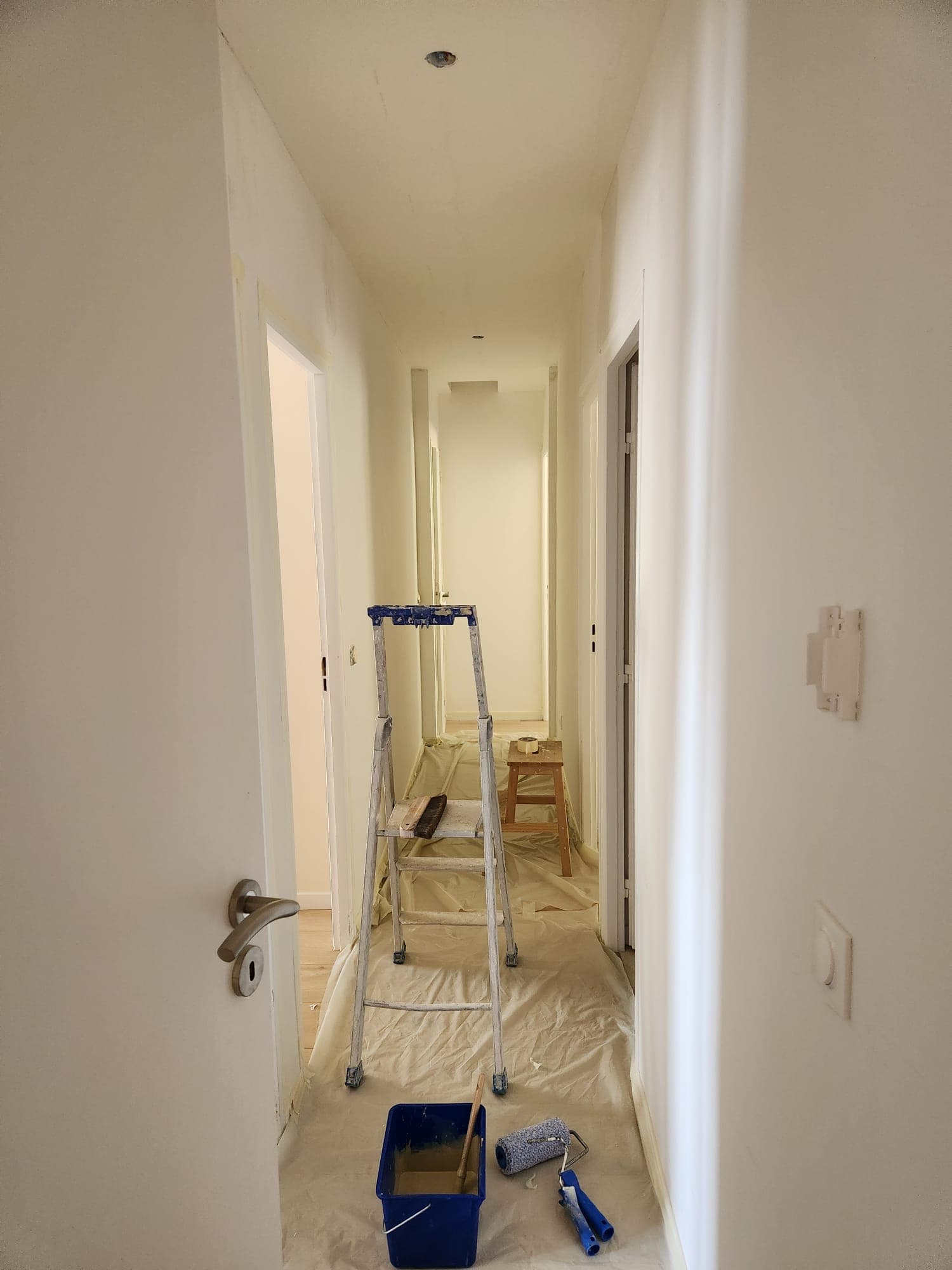 Couloir en cours de peinture au rouleau, sols protégés par Belin Travaux